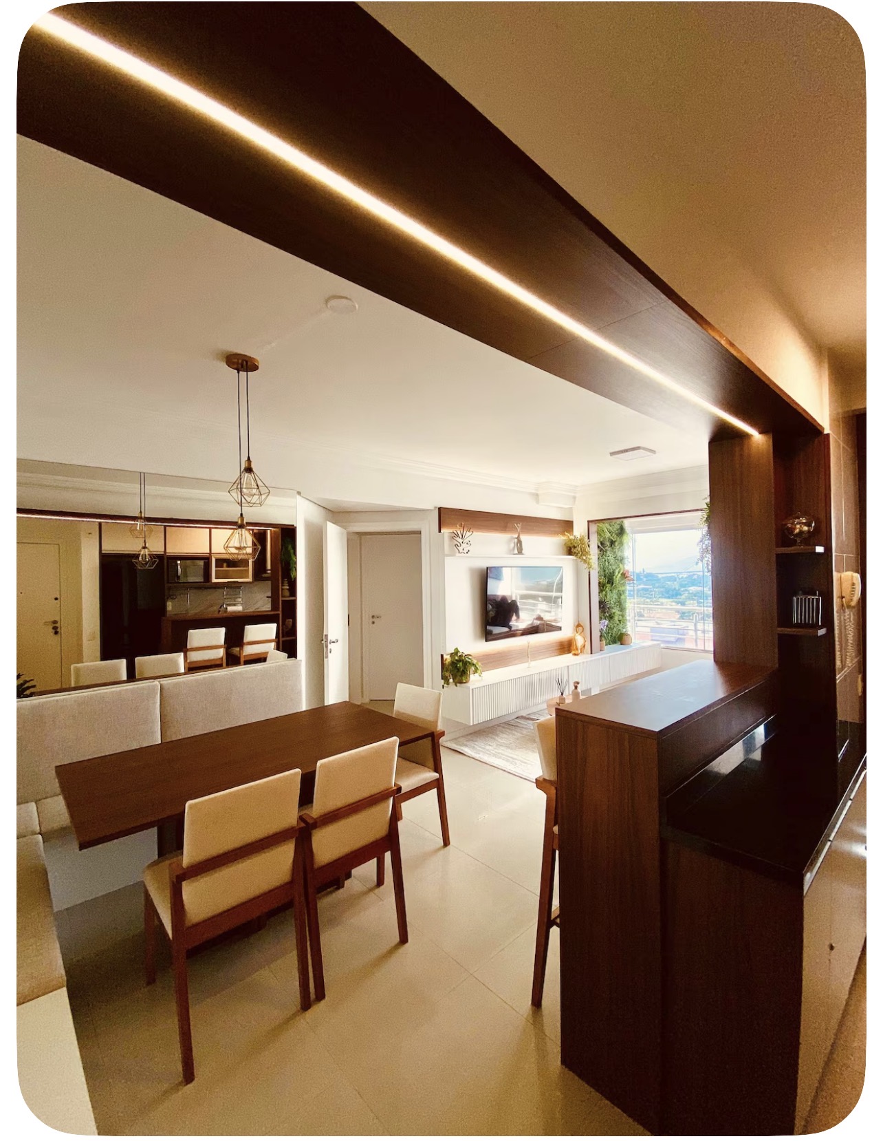 Ambiente integrado com iluminação embutida e sala de TV ao fundo