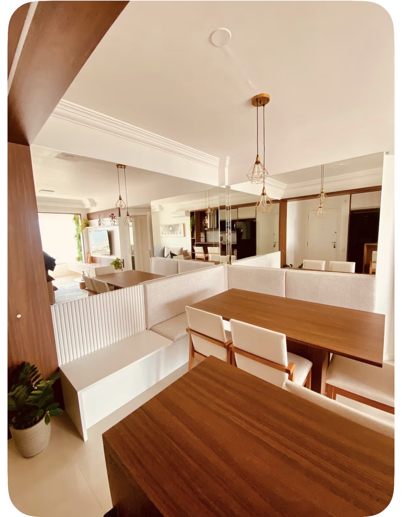Sala de jantar com mesa de madeira, banco estofado e espelho