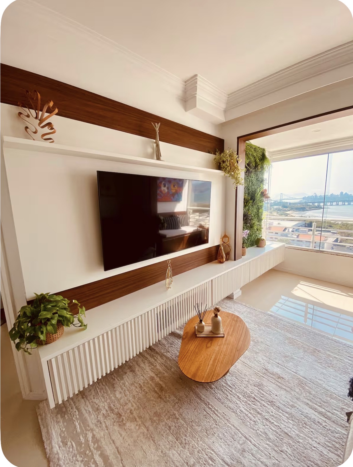 Painel de TV em madeira e jardim vertical junto à sacada